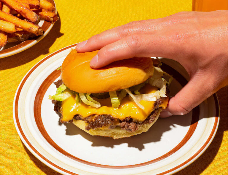 Hand grabbing single cheeseburger